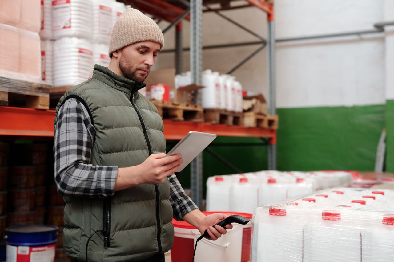 contact-img Man managing inventory with tablet in warehouse, focusing on efficiency in storage operations.
