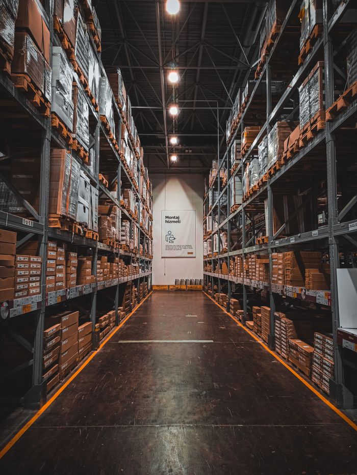 Home A well-organized warehouse aisle with stacks of goods on industrial storage racks, ensuring efficient logistics.